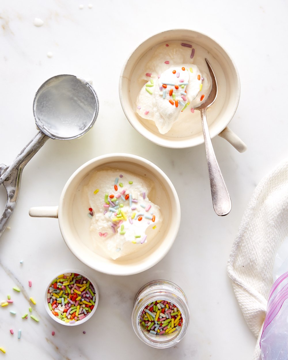 Homemade vanilla ice cream ball in spoon on ice cream container on